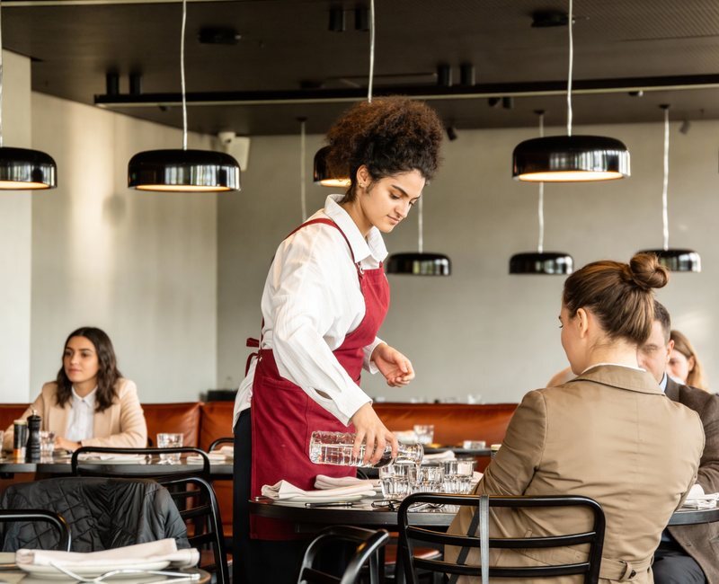 Waiter pouring water at a set table